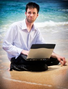 vacation ruined by work: man on beach with laptop